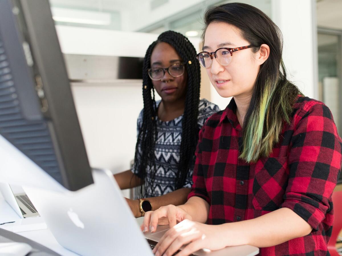 Two IT girls working on a computer.