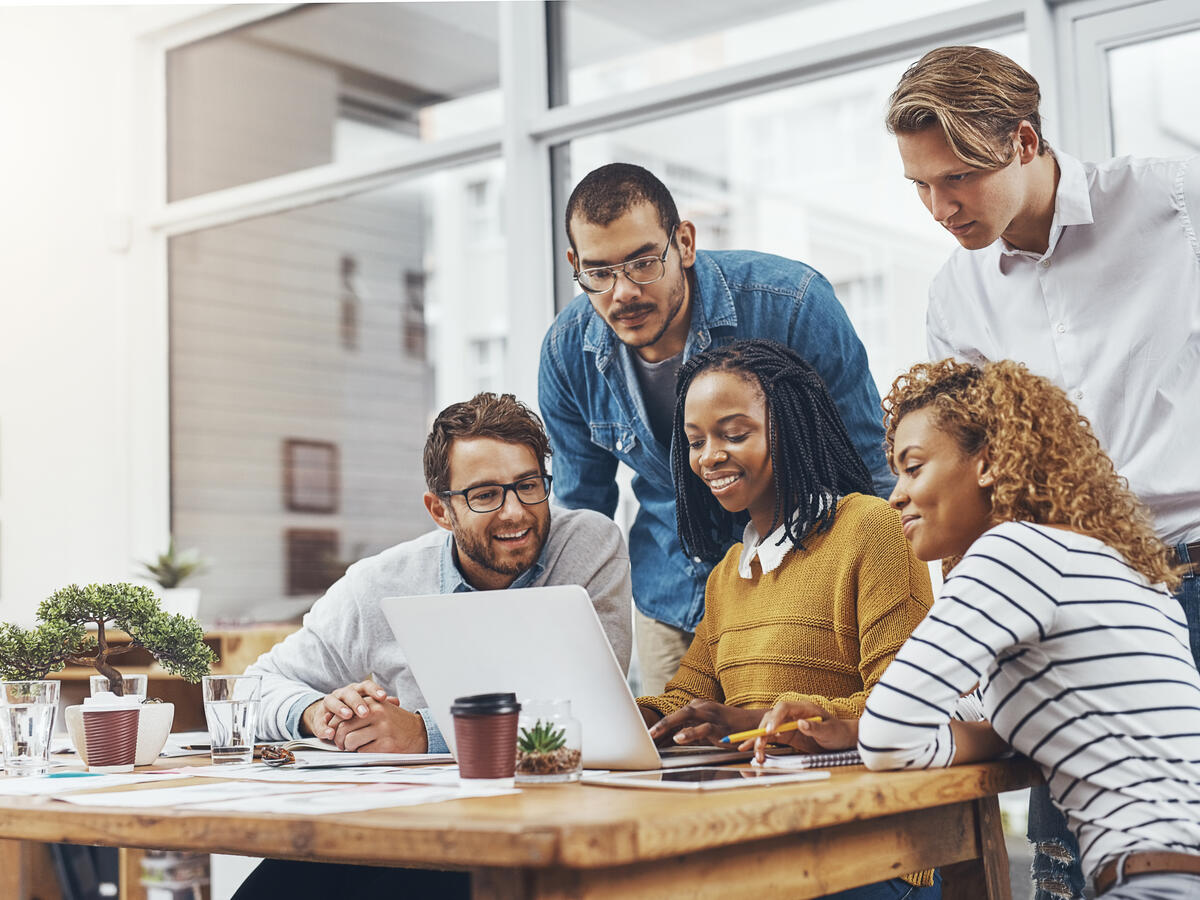 A group of 5 young people in front of a laptop.