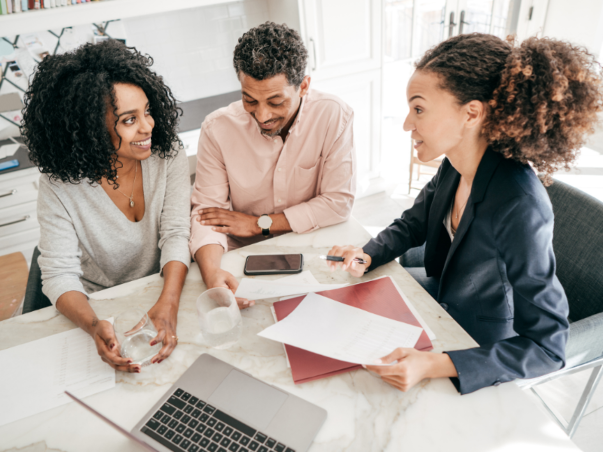 3 people around a table with laptops and documents