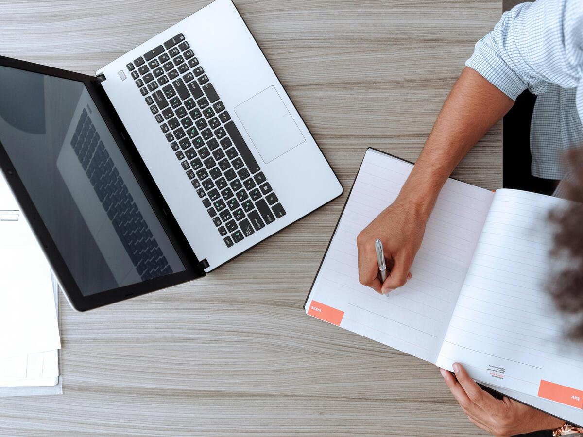 A man sitting at a desk with a laptop and a notebook.