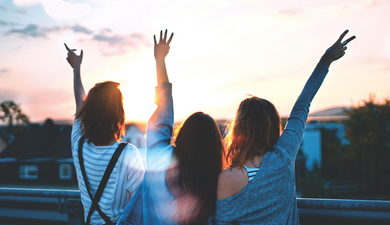 three women raising their arms joyfully