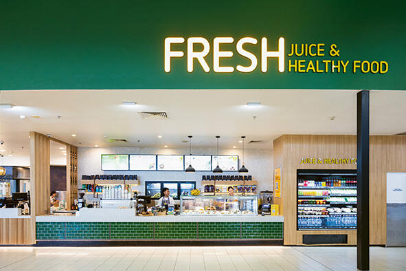 Fresh store with a green counter and a display of juices and healthy food.